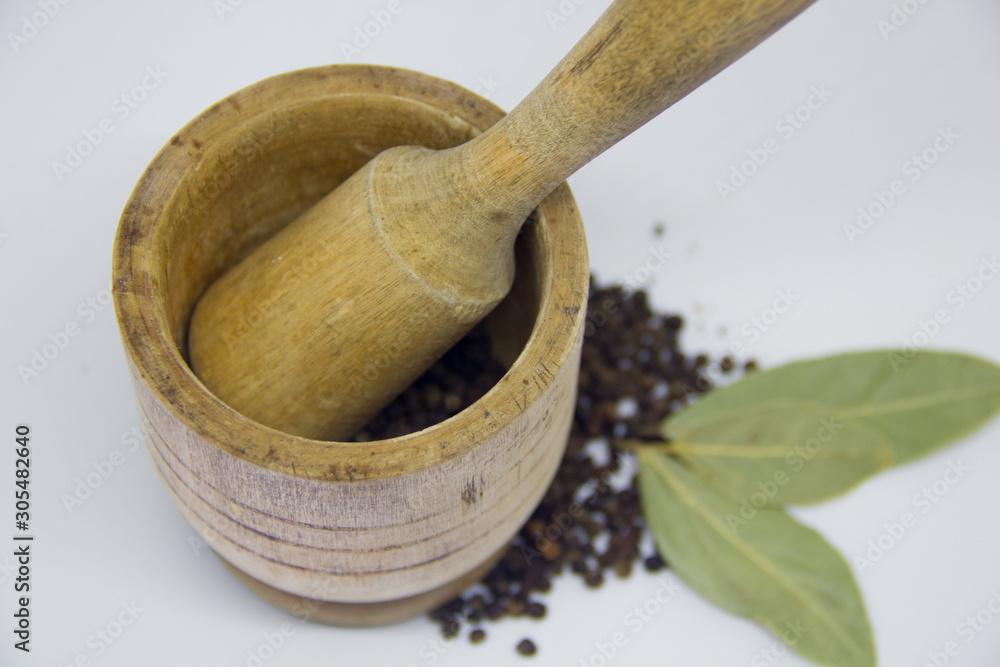 wooden mortar, black pepper, bay leaf on a white background wooden mortar, black pepper, bay leaf on a white background