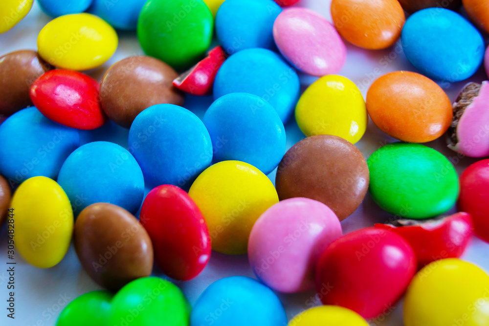 Many multi-colored small round candy pills are scattered on the table. Many multi-colored small round candy pills are scattered on the table.