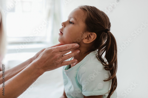 Cropped hands of doctor examining girl's throat in hospital photo