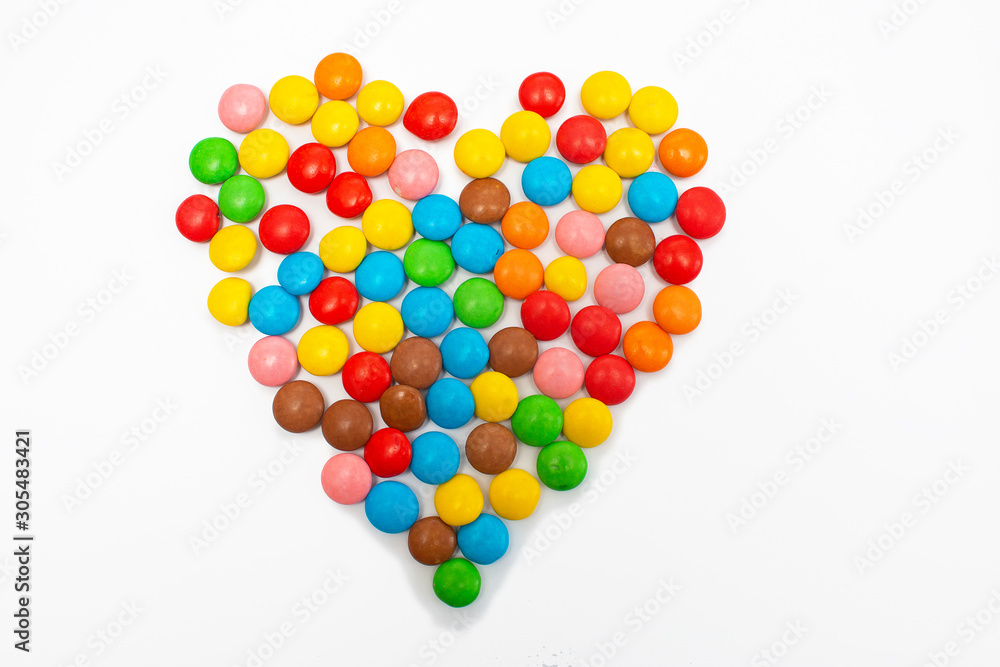 Multi-colored round candy tablets are collected in the form of a heart on a white background for Valentine's Day Multi-colored round candy tablets are collected in the form of a heart on a white background for Valentine's Day