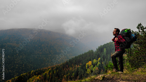 man doing trekking with a backpack. foggy mountains and autumn forest in background
