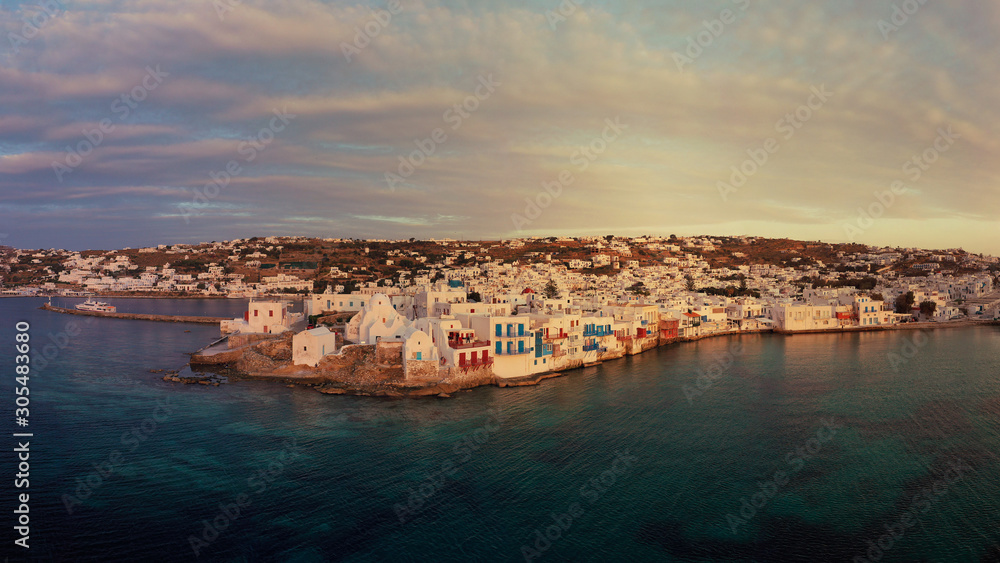 Aerial drone panoramic photo of picturesque old port in main village of Mykonos island at sunset and iconic church of Paraportiani with beautiful colours, Cyclades, Greece