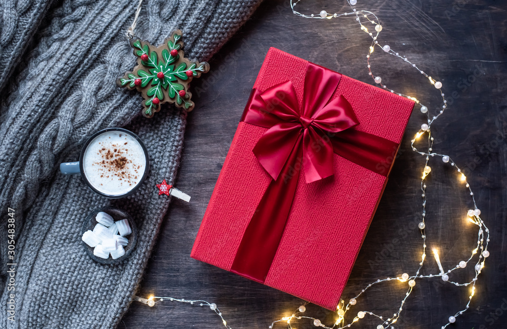 Red gift box with bow on dark wooden background. Festive garland with lights. Red gift box with bow on dark wooden background. Festive garland with lights.