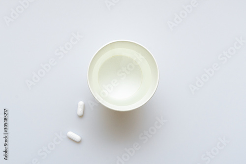 Paper cup with water and two pills