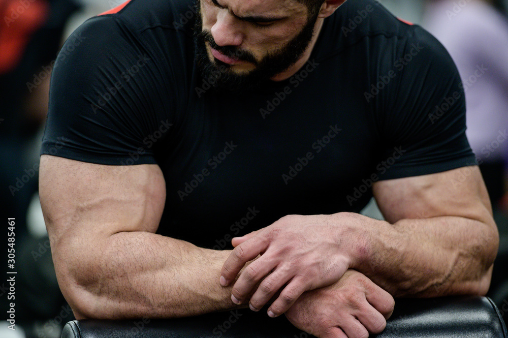 sport mental concentration concept of young strong mucle cute caucasian male with beard wearing black clothes leaning on simulator in athletic gym sport mental concentration concept of young strong mucle cute caucasian male with beard wearing black clothes leaning on simulator in athletic gym