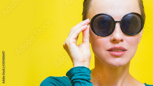 Stylish woman in sunglasses isolated over yellow background