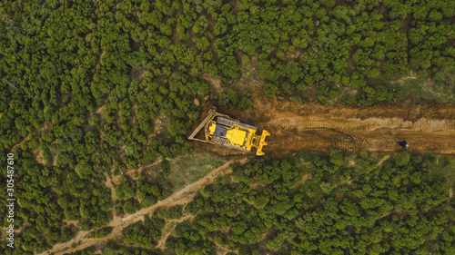 Aerial view of yellow machine doferstating beautiful trees in mountains of Marbella, Spain