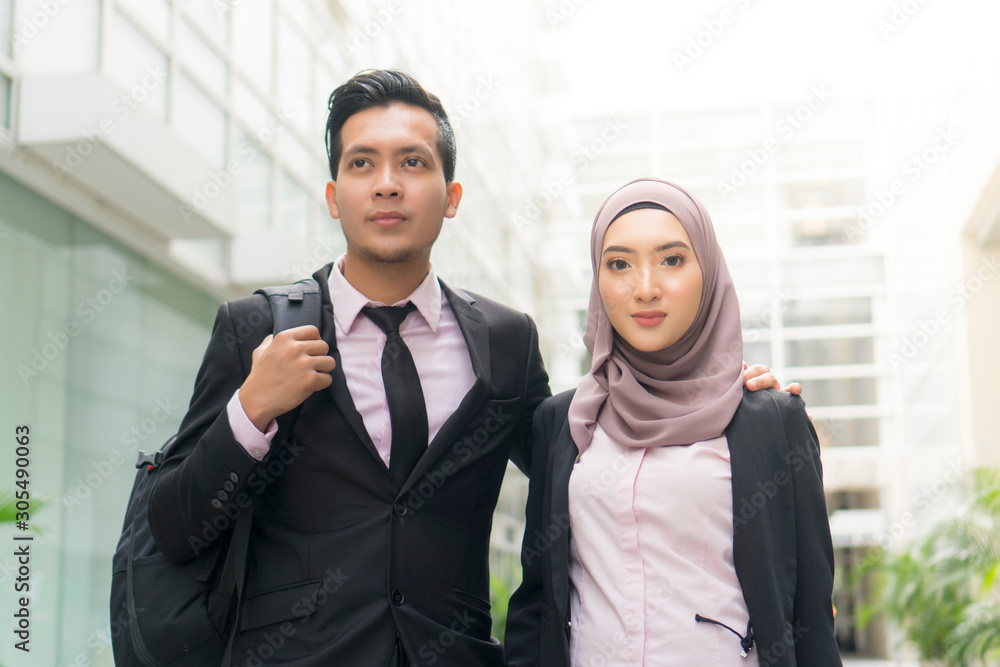 Malay Couple wearing suit walking at the office building Malay Couple wearing suit walking at the office building