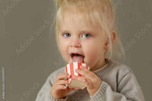  Studio shot of a toddler eating cupcakes with a whipped cream