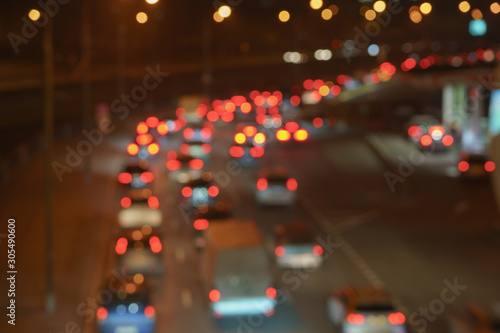 Defocused photography of urban night traffic. The lights of blurred motion at the highway. The road is filled out cars.