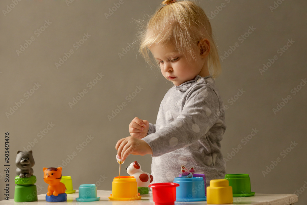 Studio shot of a toddler playing with colorful plastic cups, motor skill development. These activities for toddlers will get little hands and fingers ready for later-developing skills. Studio shot of a toddler playing with colorful plastic cups, motor skill development. These activities for toddlers will get little hands and fingers ready for later-developing skills.