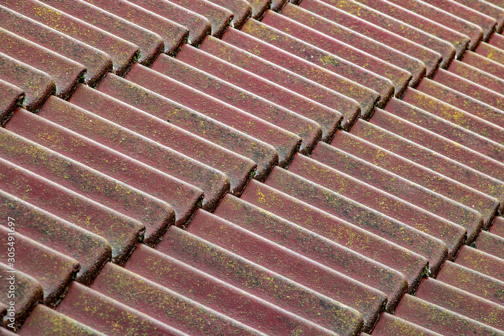 A wet roof made of concrete tiles.Diagonal view of roof with red tiles.
