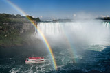 US spectators at Tarrapin Point with double rainbow ending over Hornblower tour boat at Horseshoe Falls at Niagara Falls Ontario Canada