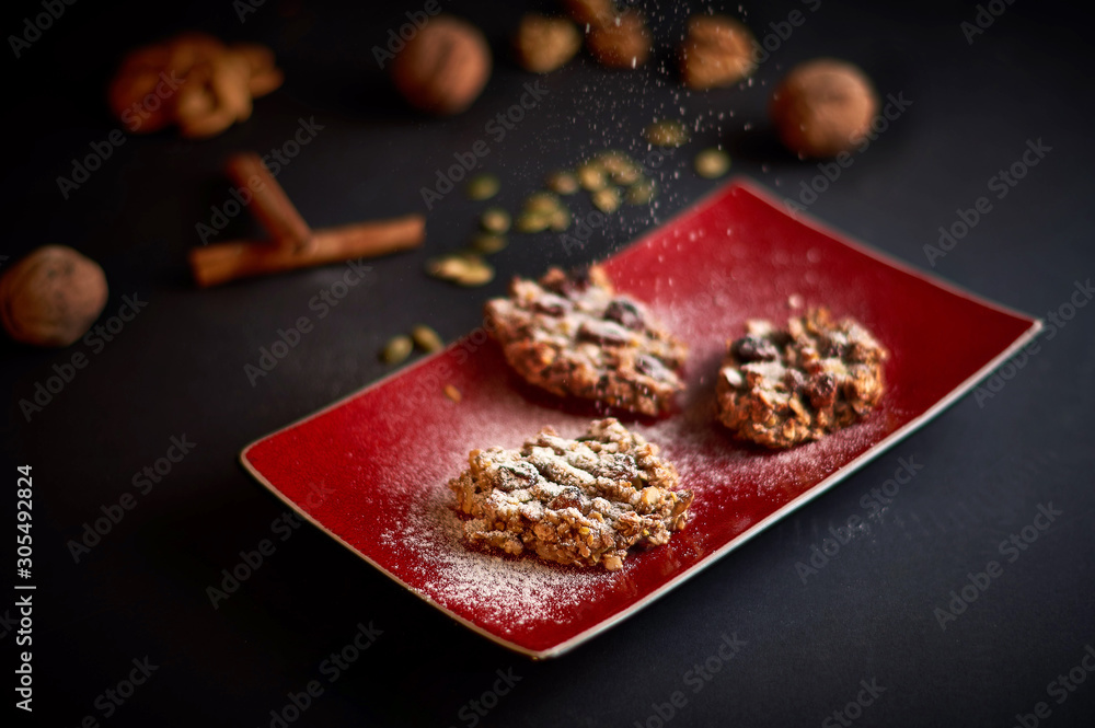 Oatmeal cookies decorated with icing sugar. Ingredients on the background - almonds, walnuts, pumpkin seeds. Oatmeal cookies decorated with icing sugar. Ingredients on the background - almonds, walnuts, pumpkin seeds.