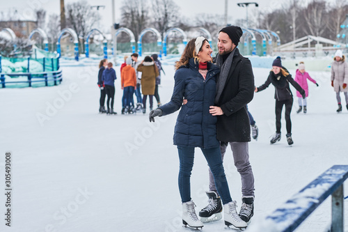 Happy couple dating in the ice rink, hugging and enjoying winter time