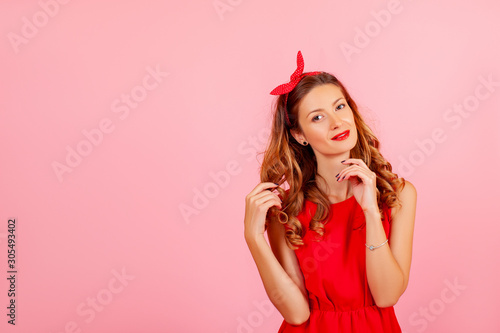 girl in red dress. Portrait of a cheerful girl in red dress and looking at camera over pink background. Copy space area for advertise, slogan or text message. Caucasian model posing in retro fashion 