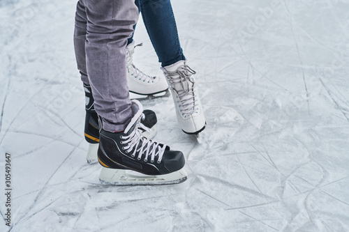 Photography Young loving couple skating at ice rink outdoors, close-up view of the skates