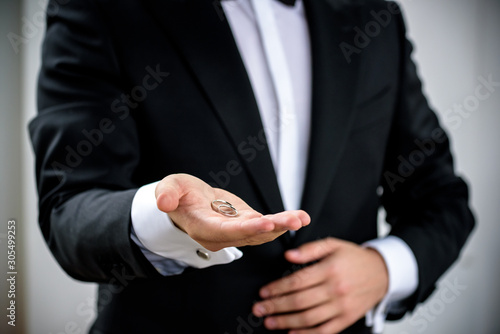Two wedding rings on groom s hand during ceremony. Groom wear black festive expensive suite. Make proposition to bride