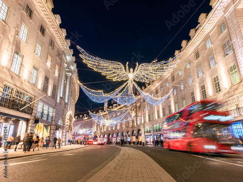 Angelic decorations illuminated and red double decker bus in motion on Regents street of London in Chrtistmas holiday, England