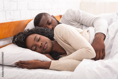 Afro couple sleeping together in comfortable bed at home