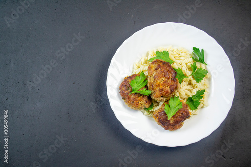 boiled pasta with meatballs on a white plate on a wooden board