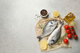 Flat lay composition with raw dorada fish on light grey table, space for text