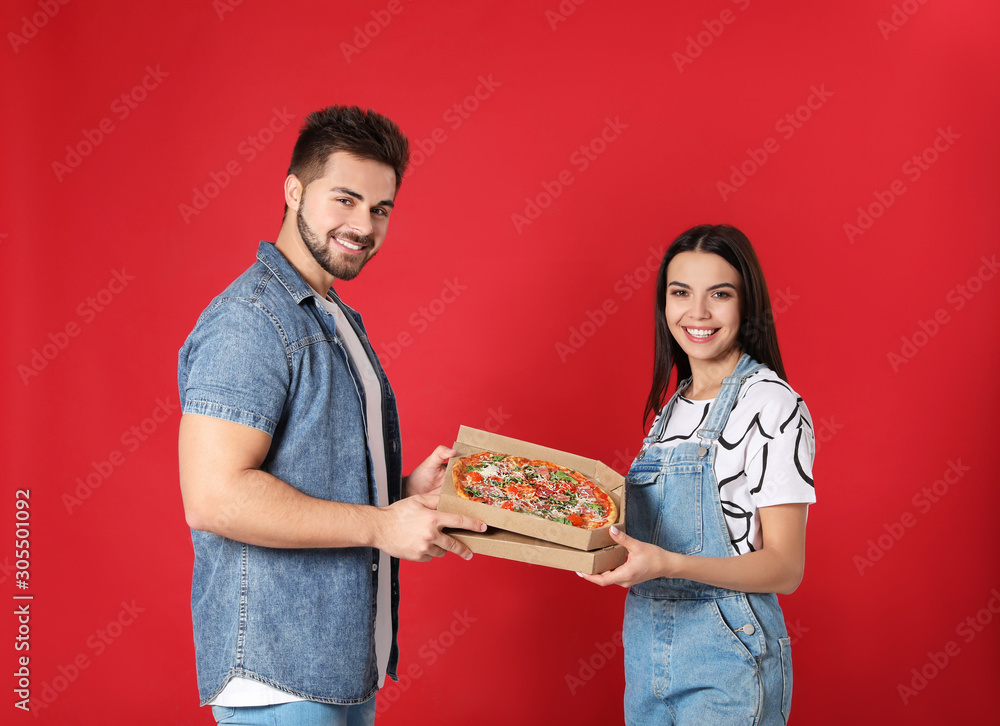 Happy young couple with pizza on red background Happy young couple with pizza on red background