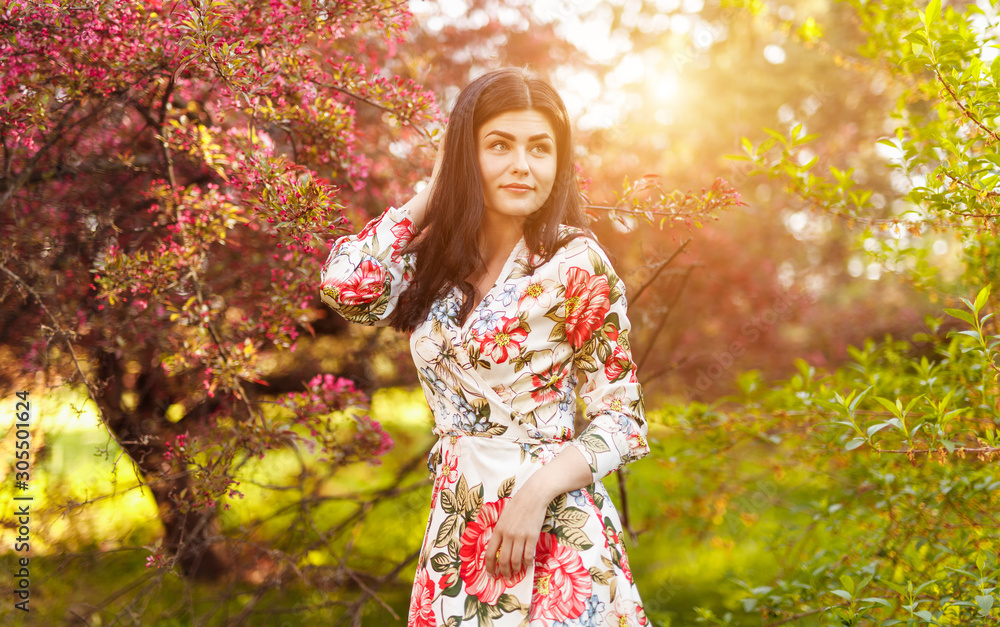 Graceful woman with charming smile in garden among flowering tree Graceful woman with charming smile in garden among flowering tree