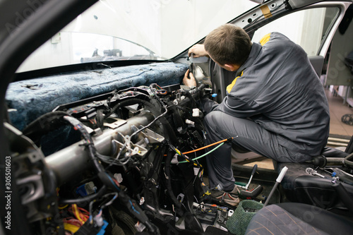 Car mechanic disassembles the interior of the car