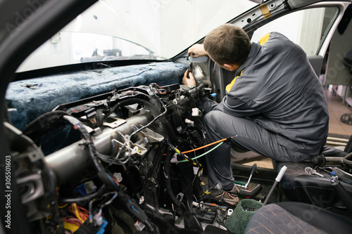 Car mechanic disassembles the interior of the car