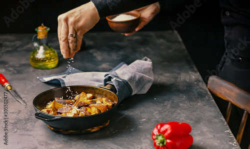 Rustic Cooking. A Woman sprinkles salt fries. Country style. photo