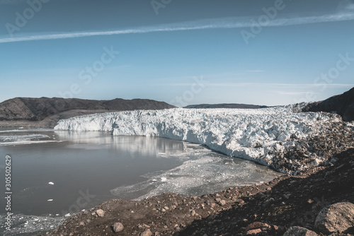 Greenland  Eqip Sermia  Eqi Glacier in Greenland Disko Bay. Boat trip in the morning over the arctic sea Baffin Bay  calving glacier. Ice breaking of on a blue sky wth clouds.