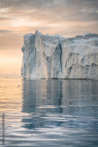 Iceberg at sunset. Nature and landscapes of Greenland. Disko bay. West Greenland. Summer Midnight Sun and icebergs. Big blue ice in icefjord. Affected by climate change and global warming. photo