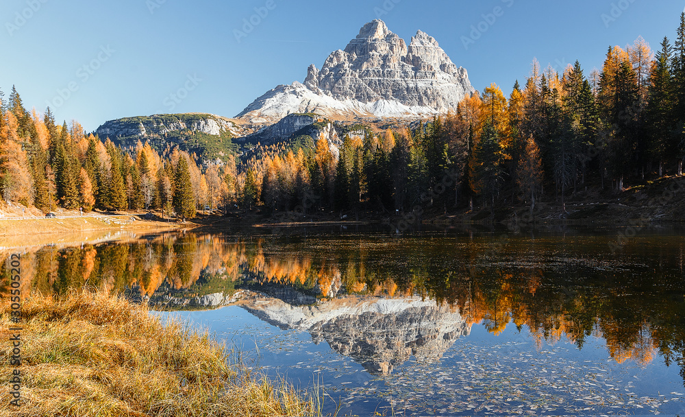 Famous peak of Tre Cime di Lavaredo under bright sunlight during sunrise. Stunning evening view on Antorno Lake with reflection of majestic  Dolomites, Italy Europe. Amazing nature scenery.