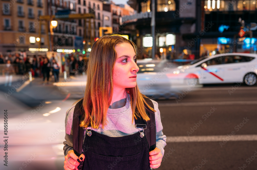 Young woman standing at night in the city on the street