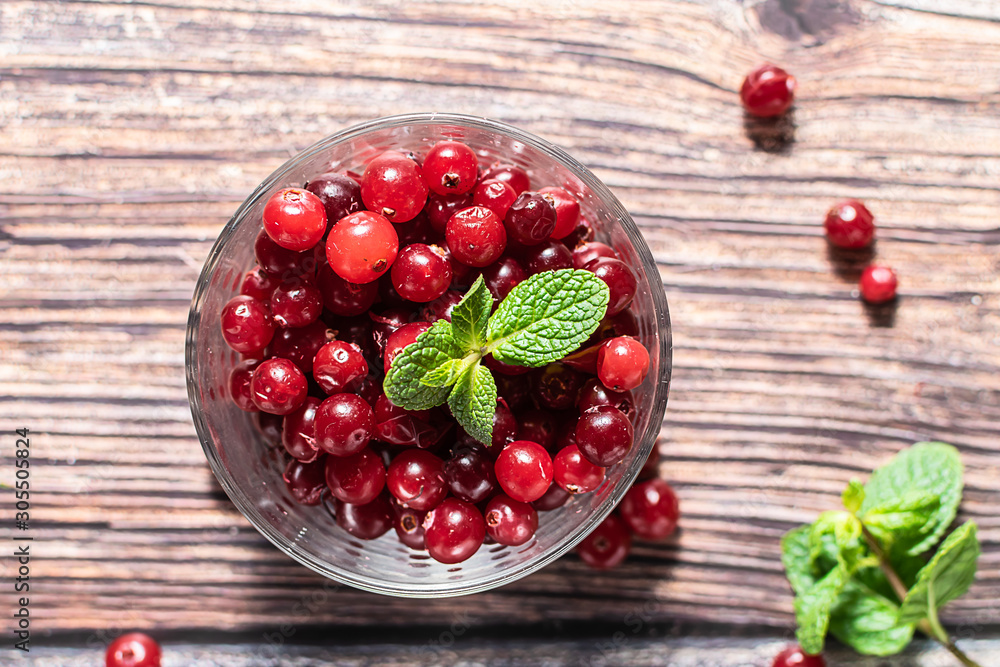 Fresh organic ripe Cranberries in a glass bowl on rustic wooden table top view. Fresh organic ripe Cranberries in a glass bowl on rustic wooden table top view.