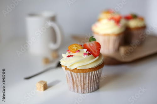 cupcake with cream cheese decorated with strawberries on a white background.