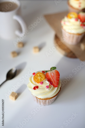 cupcake with cream cheese decorated with strawberries on a white background.