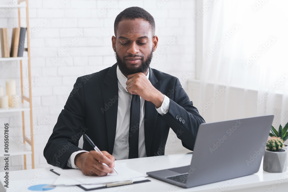 Fototapeta premium Serious young manager signing documents in his office