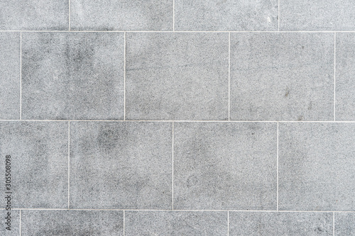 Texture of gray road granite tiles with white seams. Stone background.