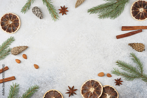 Christmas composition on a light background. Cinnamon, anise, almonds, cones, slices of orange, spruce branches form a frame for text. Free space for text.