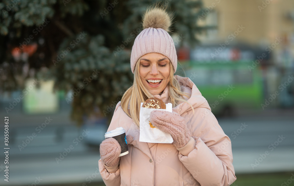 Beautiful smiling young woman in warm clothing with cup of hot tea coffee or punch. Woman eating cookies outdoor. Beautiful smiling young woman in warm clothing with cup of hot tea coffee or punch. Woman eating cookies outdoor.