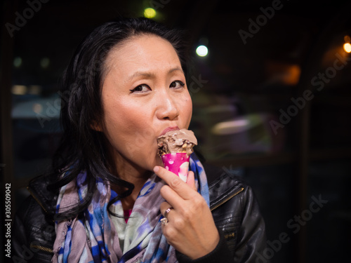 Photography Young Asian woman enjoying a chocolate ice cream cone.