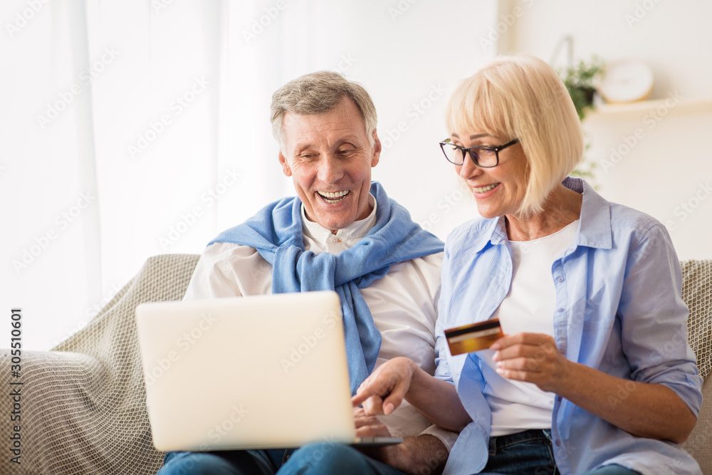 Shopping online. Senior spouses making purchases on laptop Shopping online. Senior spouses making purchases on laptop