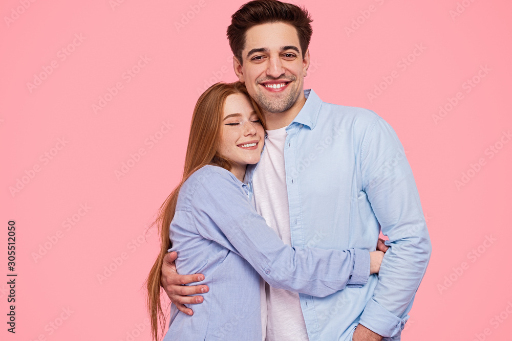 Smiling long haired woman hugging man looking at camera Smiling long haired woman hugging man looking at camera