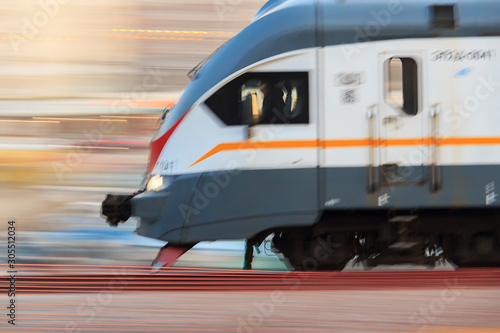 Blurred stripes and tracing from headlights. Electric train in motion. electric multiple unit. High speed  train in motion on railway station at sunset. Modern intercity passenger train with blur way photo