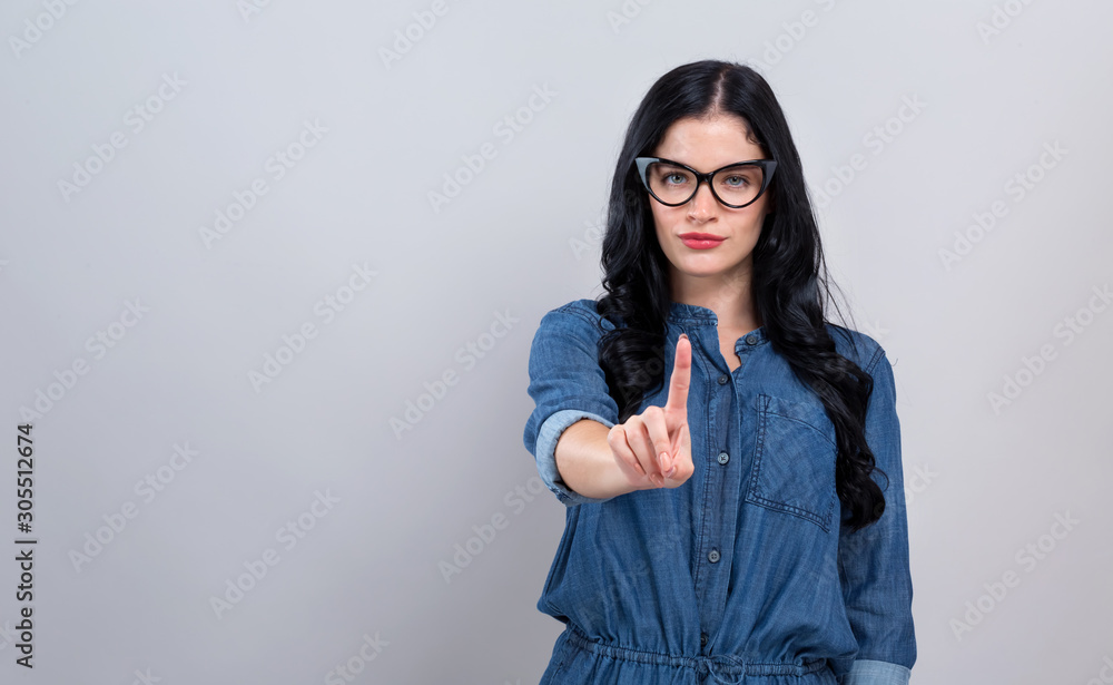 Young woman pointing at something on a gray background Young woman pointing at something on a gray background