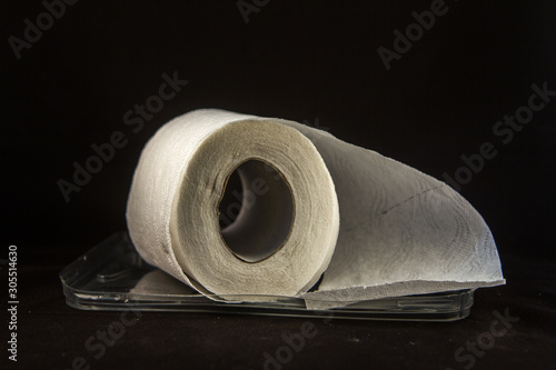 Unrolled toilet paper that gets wet and absorbs the liquid on a black background