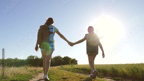 teamwork tourists teenagers. Woman travelers walk on road in the countryside. happy hiker girl in summer park. Happy girls travelers go with backpacks in field. teenager girl adventures on vacation.