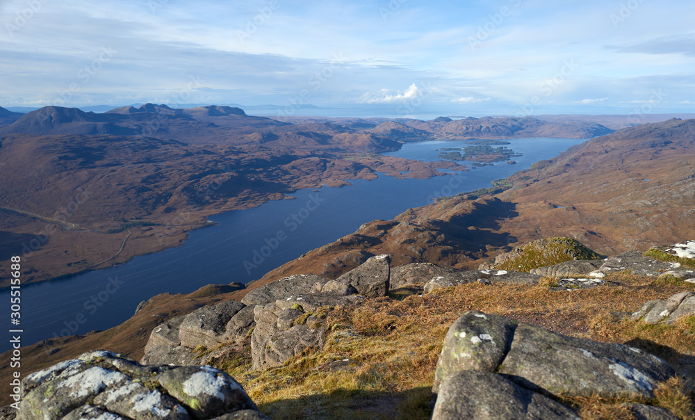 Views of Loch Maree and Flowerdale Forest in the distance from the rocky summit of Slioch in the Scottish Highlands on a sunny winters day.